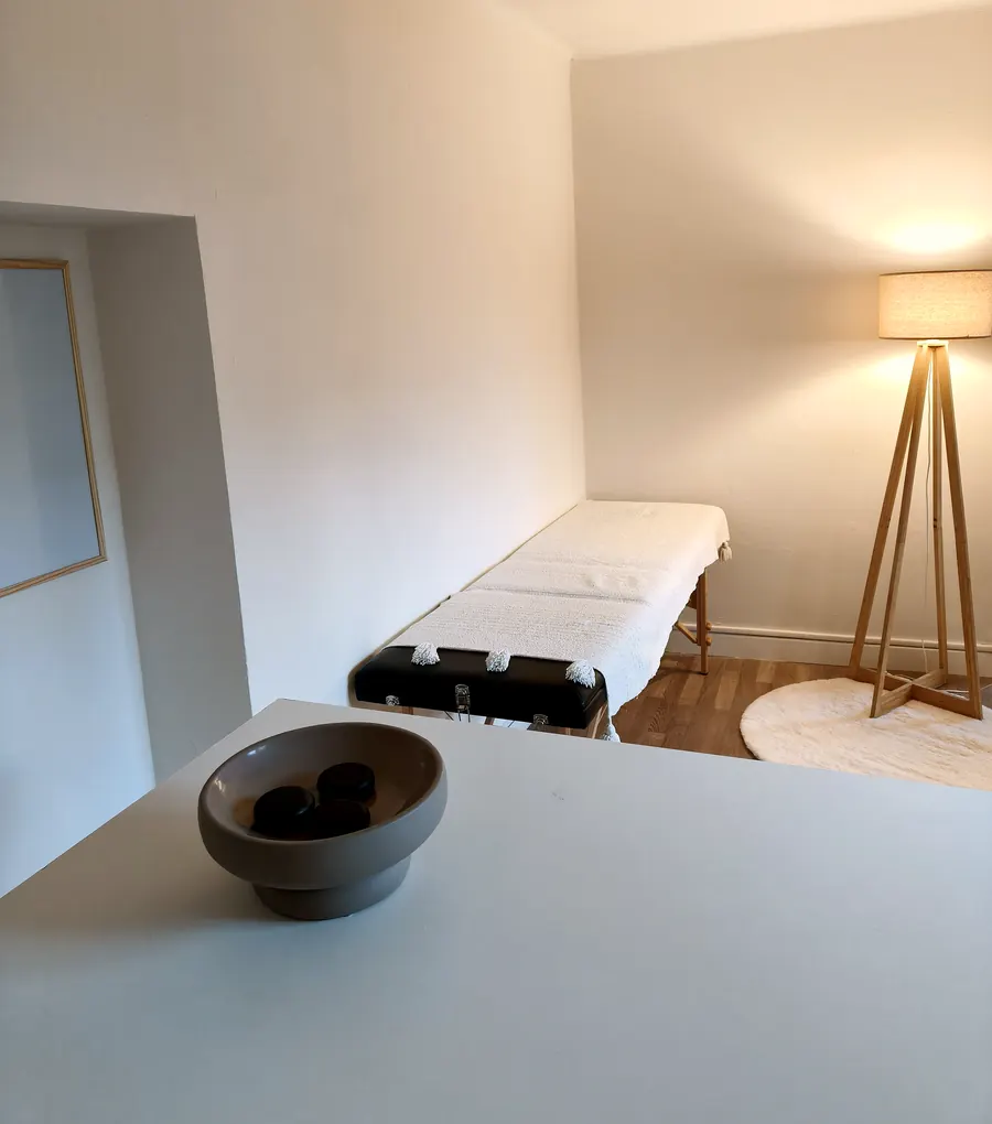 Le cabinet de MagnétiSanté : table de séance recouverte d'un plaid blanc, lampadaire en bois et tapis clair